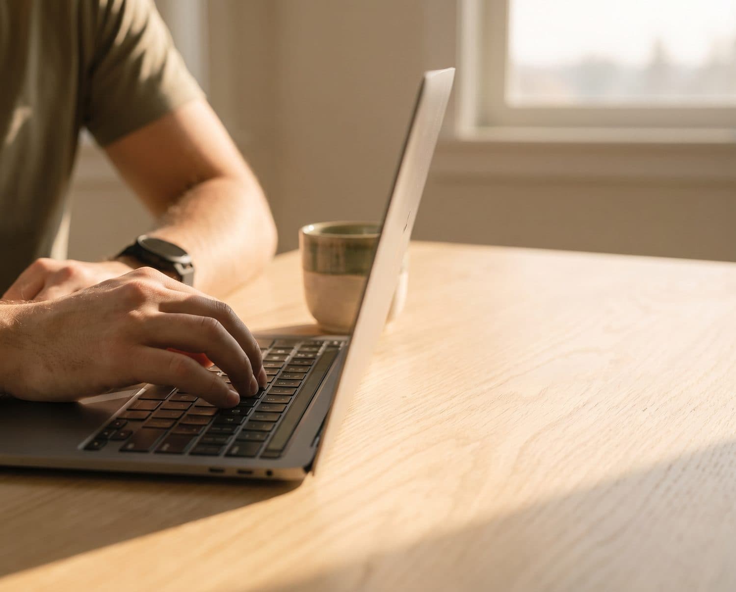 Hand typing on a laptop with a sports watch on the wrist